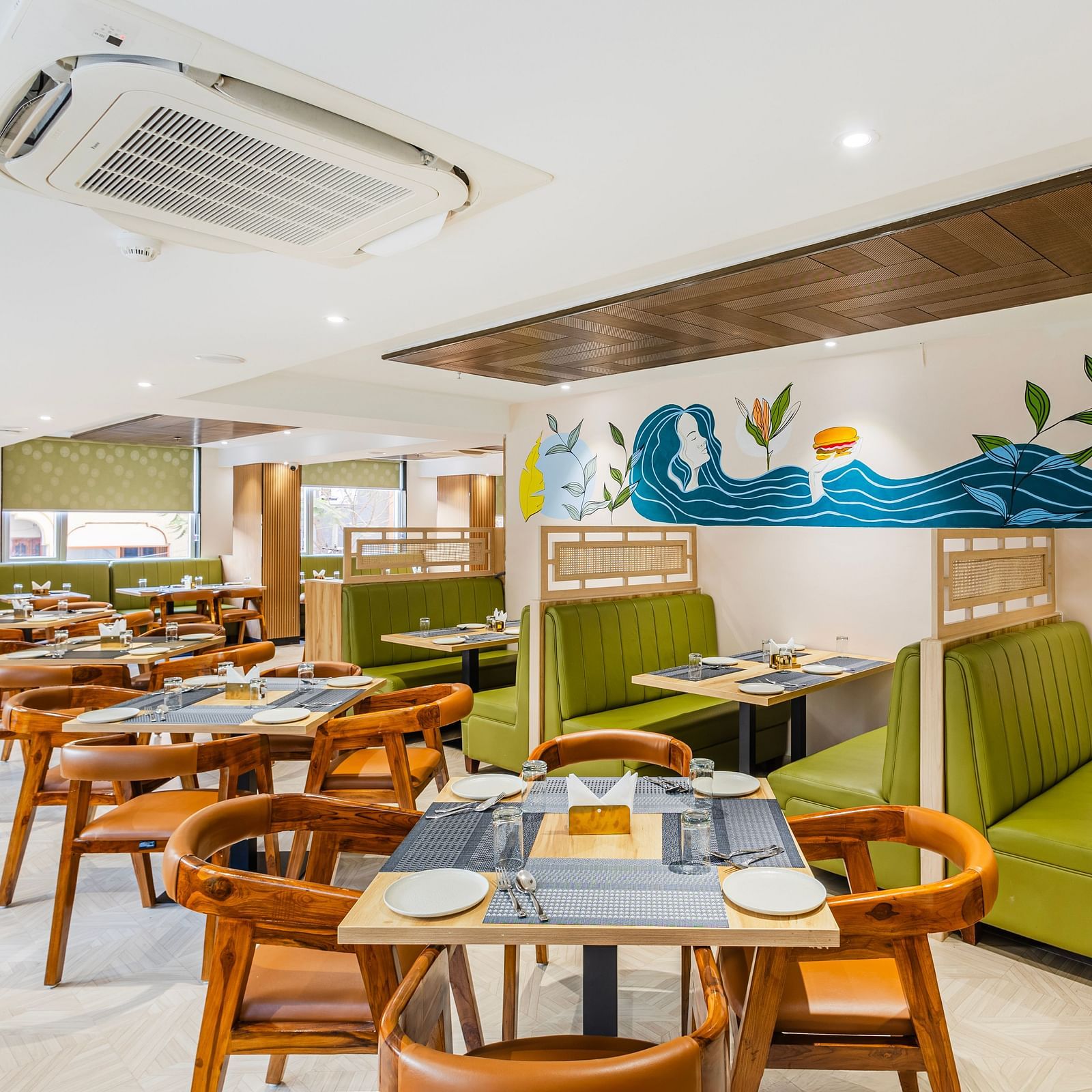 Lemonridge Hotels, KPHB | Dining area with tables and chairs, showcasing the artistic wall decor and ceiling design.